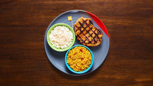 Chicken Butterfly on a plate with optional sides Coleslaw and Spicy Rice