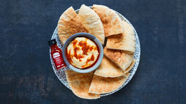 Houmous & PERi-PERi Drizzle served with warm pitta triangles on a plate
