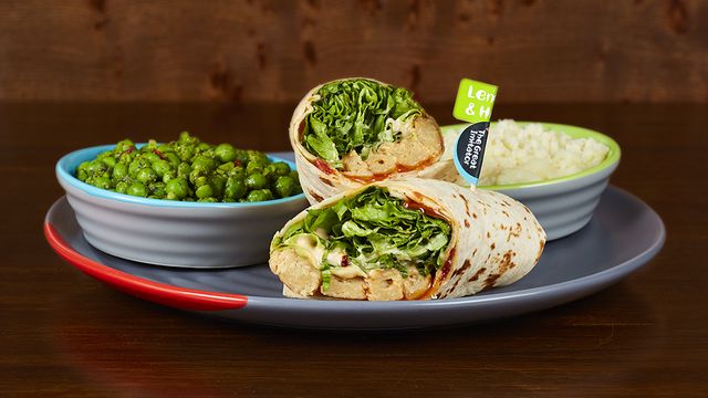 The Great Imitator Wrap on a plate with optional sides Macho Peas and Creamy Mash